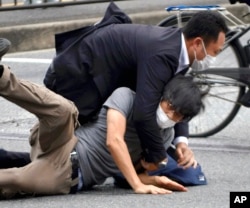 Tetsuya Yamagami, bottom, is detained near the site of gunshots in Nara Prefecture, western Japan, July 8, 2022.