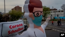 An inflatable representation of a doctor points to a coronvirus rapid test center, in Frankfurt, Germany, March 29, 2022. 