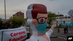 An inflatable representation of a doctor points to a coronvirus rapid test center, in Frankfurt, Germany, March 29, 2022. 