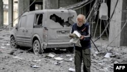 3일 가자시티의 파괴된 자동차 인근에서 팔레스타인인이 책을 읽고 있다. 