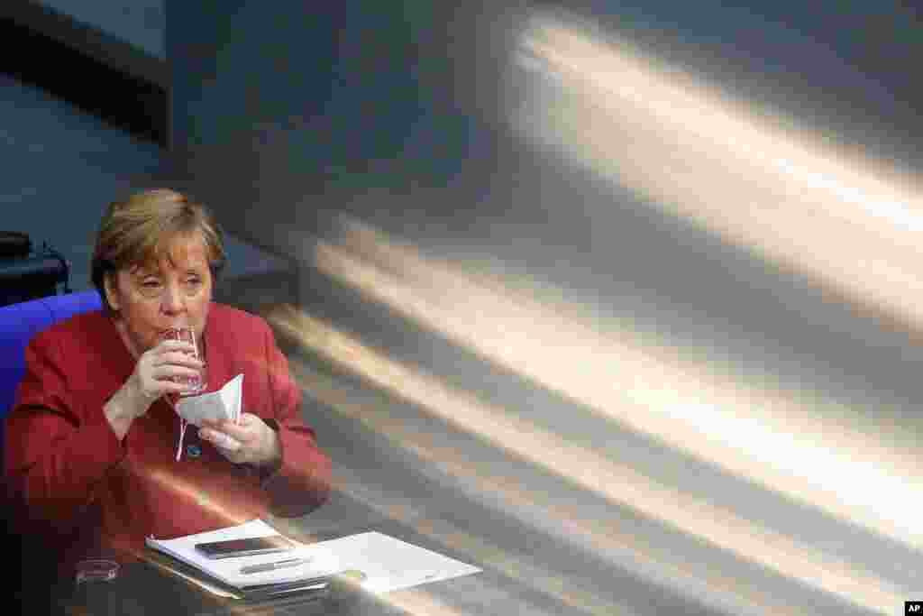 German Chancellor Angela Merkel drinks some water during a parliament session about a new law to battle the coronavirus pandemic at the Bundestag at the Reichstags building in Berlin, Germany.