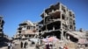 FILE - A man cycles past vendors offering goods for sale outside heavily damaged buildings in a camp sheltering people displaced by the Israel-Hamas conflict, in Jabalia in the northern Gaza Strip, Sept. 8, 2024.