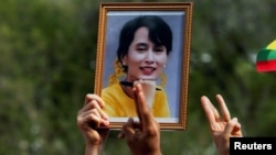 A person holds a picture of leader Aung San Suu Kyi as Myanmar citizens protest against the military coup in front of the U.N. office in Bangkok, Thailand, Feb. 22, 2021.