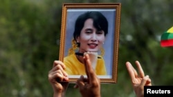 FILE - A person holds a picture of leader Aung San Suu Kyi as Myanmar citizens protest against the military coup in front of the UN office in Bangkok, Thailand Feb. 22, 2021.