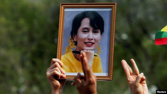 A person holds a picture of leader Aung San Suu Kyi as Myanmar citizens protest against the military coup in front of the UN office in Bangkok, Thailand Feb. 22, 2021.
