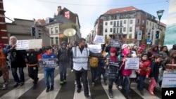 An organizer leads children holding signs out of the Molenbeek district during a march against hate in Brussels on Sunday, April 17, 2016. 