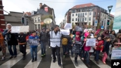 Seorang demonstran memimpin anak-anak berbaris keluar dari distrik Molenbeek dalam unjuk rasa melawan kebencian di Brussels (17/4). (AP/Virginia Mayo)