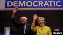 Senator Bernie Sanders (kiri) dan Hillary Clinton ketiba tiba untuk berdebat hari Kamis (11/2) malam di Milwaukee, Wisconsin.