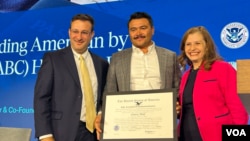 El ciudadano naturalizado de origen mexicano, Osiris Hoil, centro, propietario de District Tacos recibe reconocimiento por parte de la directora de USCIS, Ur M. Jaddou, derecha, por su aporte a la comunidad como emprendedor en los negocios. A la izquierda Ron Rosenberg, de USCIS.