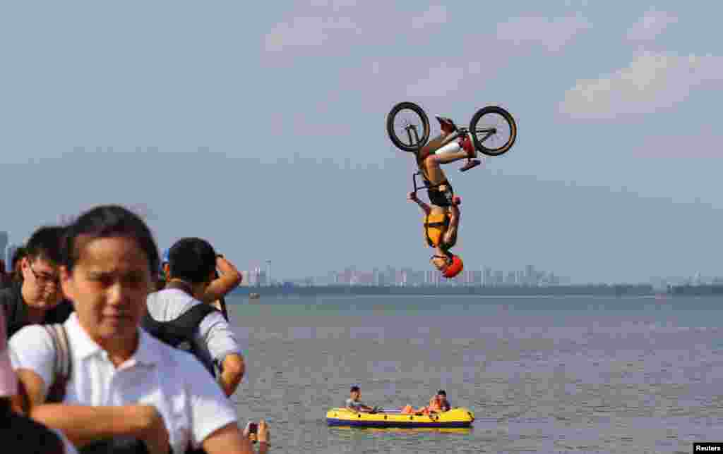 A man performs a BMX bicycle trick as he jumps into East Lake in Wuhan, Hubei Province, China Aug. 19, 2017.
