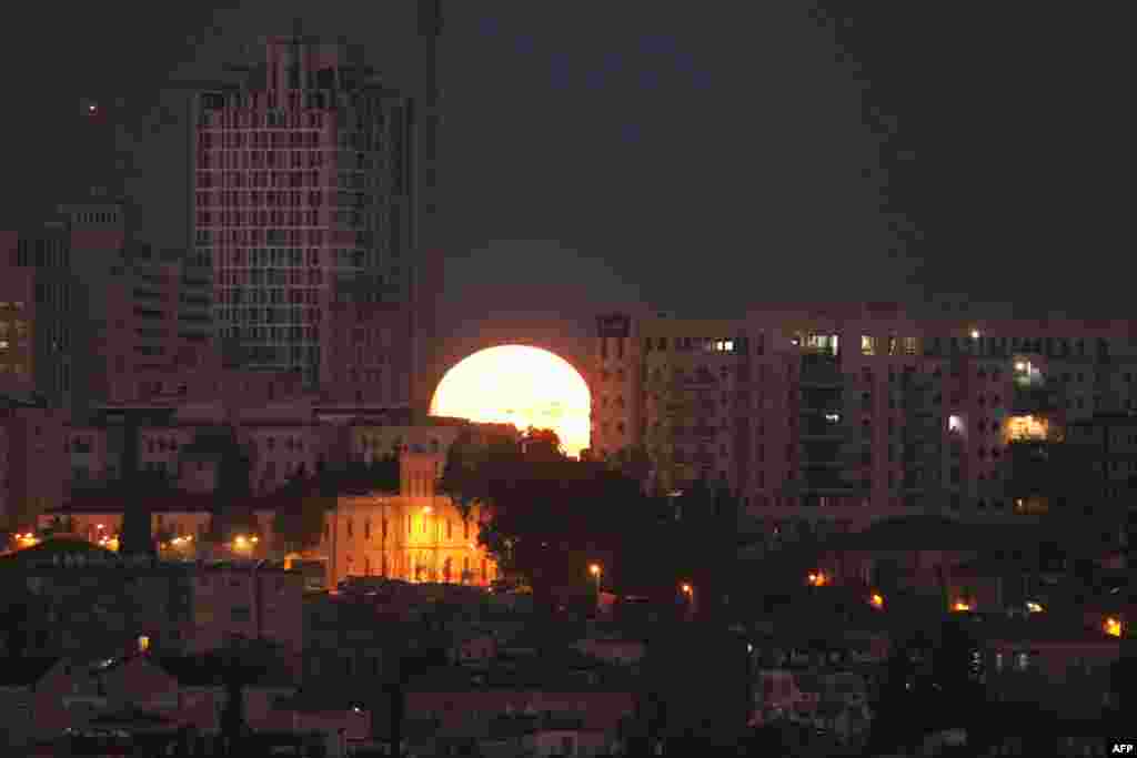 The moon sets behind the city of Jerusalem.