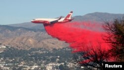 A plane drops fire retardant on the Maria Fire in the early morning in Santa Paula, California, Nov. 1, 2019. 