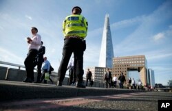 Commuters walk past a police officer on London Bridge in London, June 5, 2017.