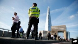 Commuters walk past a police officer on London Bridge in London, June 5, 2017.