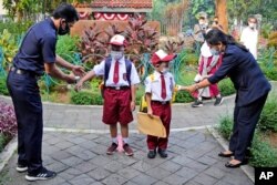 Petugas memeriksa suhu tubuh siswa pada hari pertama pembukaan kembali sekolah di Jakarta, Senin, 30 Agustus 2021. (Foto: AP)