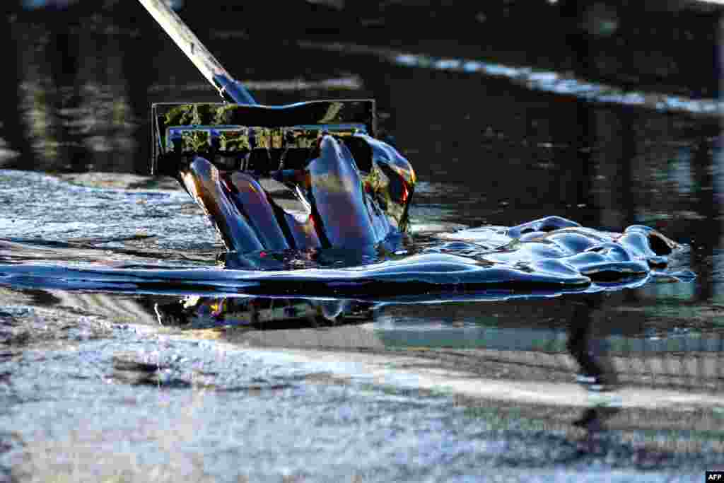 A worker cleans up an oil from a pipe that burst causing about 10,000 gallon of crude oil spill onto streets covering an area of about a half-mile in Los Angeles, California.