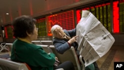Chinese stock investors look over a newspaper in a brokerage house in Beijing, Jan. 27, 2016. Chinese stocks sank again Wednesday but other Asian markets rose following Wall Street's gain.