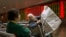 Chinese stock investors look over a newspaper in a brokerage house in Beijing, Jan. 27, 2016. Chinese stocks sank again Wednesday but other Asian markets rose following Wall Street's gain.