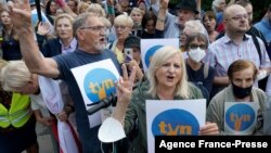 FILE - In this file photo taken on Aug. 10, 2021 protesters show the victory sign as they hold up placards with the letters of Poland's main private TV network TVN, a US-owned broadcaster, as they demonstrate in defence of media freedom in Warsaw.