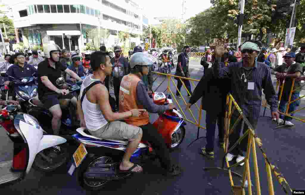 Anti-government protesters man a barricade to prevent traffic from entering an intersection in central Bangkok, Jan. 13, 2014.