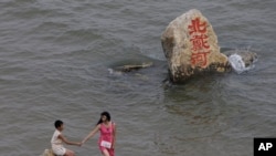 资料照 - 2008年8月8号，一位妇女和一名孩子在河北省秦皇岛北戴河的海滩上游玩。