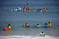 Children perform activities with surfing boards at the Mediterranean Sea during a summer camp in Ashkelon, Israel July 10, 2019. (REUTERS/Amir Cohen)