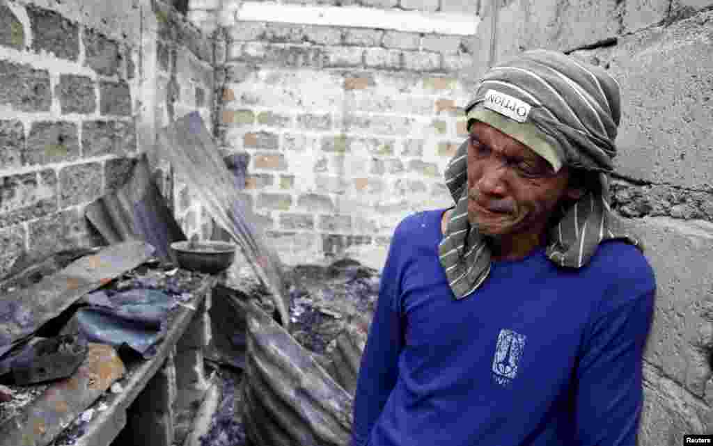 A man weeps in the ruins of his house razed by a fire, in Paranaque, Metro Manila in the Philippines. More than 1,000 residents were rendered homeless after a fire razed the residential neighborhood of San Martin de Porres.