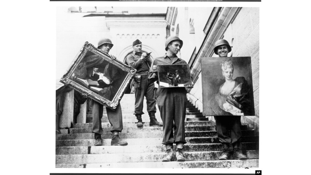This photo provided by The Monuments Men Foundation for the Preservation of Art of Dallas, shows Monuments Man James Rorimer, with notepad, as he supervises American GI's hand-carrying paintings down the steps of the castle in Neuschwanstein, Germany in May, 1945.