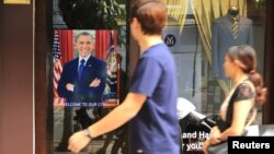 Warga melewati poster Presiden AS Barack Obama yang bertuliskan "Selamat Datang di Kota Kami" di sebuah pintu bangunan di Hanoi (22/5). (AP/Hau Dinh)