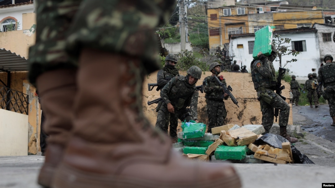 Brazilian soldiers and Civil Policemen carry drugs seized in the woods of Chatuba slum during an operation against drug dealers in Rio de Janeiro, Brazil, Aug. 22, 2018.