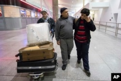 Ali Abdullah Alghazali, 13, right, from Yemen, wipes his eyes as he walks with his father Abdullah Alghazali, left, and his uncle after arrival at John F. Kennedy International Airport in New York, Feb. 5, 2017.