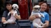 Animal activists hold a dog rescued from a dog meat trader (R) and a rescued stray dog, before a gathering against the Yulin Dog Meat Festival in Beijing, China, June 10, 2016.