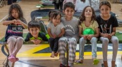 Anak-anak berpose di gym di lokasi yang dirahasiakan di wilayah Timur Tengah, Jumat, 20 Agustus 2021, setelah dievakuasi di atas pesawat militer dari Bandara Internasional Hamid Karzai di Kabul, Afghanistan.(Kylie Barrow, U.S Air Force via AP)
