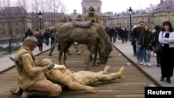 Les Parisiens passent devant une exposition sur le Pont des Arts présentée par le sculpteur Ousmane Sow, le 18 mars 1999.