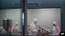 Scientists re-enact the calibration procedure of equipment at an Afrigen Biologics and Vaccines facility in Cape Town, South Africa, Tuesday Oct. 19, 2021.