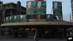 An Egyptian woman walks under electoral posters supporting the ruling National Party with a picture of Gamal Mubarak, son of President Hosni Mubarak, ahead of the upcoming Nov. 28 parliamentary elections, in Alexandria, Egypt, 27 Nov 2010