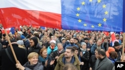 Protesters wave Polish and European Union flags during an anti-government demonstration in Warsaw, Poland, Dec. 19, 2015.