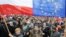 Protesters wave Polish and European Union flags during an anti-government demonstration in Warsaw, Poland, Dec. 19, 2015.