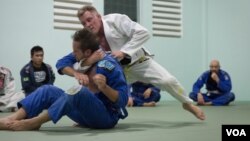Chris Haueter (in white), one of the well-known BJJ trainers, shows a Jiu Jitsu's technique to a group of expats during a training session at the Olympic Stadium, in Phnom Penh, on February 22, 2016. (Neou Vannarin/VOA Khmer)