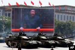 Chinese President Xi Jinping is displayed on a screen as Type 99A2 Chinese battle tanks take part in a parade commemorating the 70th anniversary of Japan's surrender during World War II held in front of Tiananmen Gate in Beijing, Thursday, Sept. 3, 2015.