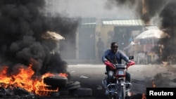 Un motociclista conduce a través de una barricada en llamas, en uno de los varios vecindarios que los residentes se vieron obligados a abandonar debido a la escalada de la violencia, en Puerto Príncipe, Haití, el 18 de enero de 2024.