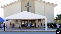 People practice social distancing as they wait at a COVID-19 testing site at Sacred Heart Church, May 5, 2020, in Lake Worth, Fla. 