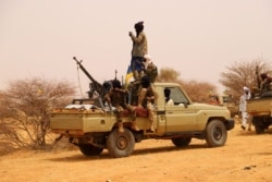 FILE - An anti-aircraft gun is mounted on the back of a pickup truck as militants from a Tuareg political and armed movement in the Azawad Region in Mali gather in the desert outside Menaka, March 14, 2020.