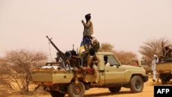 FILE - An anti-aircraft gun is mounted on the back of a pickup truck as militants from a Tuareg political and armed movement in the Azawad Region in Mali gather in the desert outside Menaka, March 14, 2020.