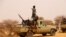 FILE - An anti-aircraft gun is mounted on the back of a pickup truck as militants from a Tuareg political and armed movement in the Azawad Region in Mali gather in the desert outside Menaka, March 14, 2020.