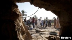 Orang-orang terlihat melalui lubang rumah yang rusak akibat serangan roket, di distrik Abu Ghraib, di pinggiran Baghdad, Irak, 29 September 2020. (Foto: REUTERS/Saba Kareem)