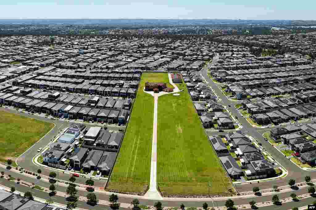 This aerial view shows a single property on a large piece of land amid a densely developed area with many homes in Sydney, Australia.