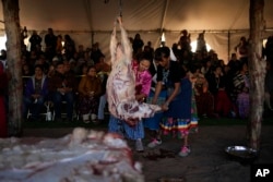 Miss Navajo Nation pageant contestant Amy Begaye, left, butchers a sheep with help from Kashlynn Benally during a sheep-butchering contest, Monday, Sept. 4, 2023, on the Navajo Nation in Window Rock, Ariz. (AP Photo/John Locher)