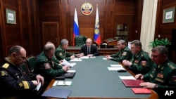 Russian President Vladimir Putin, center, leads a meeting with top military officers in the National Defense Control Center in Moscow, Dec. 24, 2019.