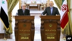 Menlu Suriah Walid Moallem (kiri) dan Menlu Iran Mohammad Javad Zarif mengutuk serangan Israel dalam konferensi pers di Teheran, Senin (8/12).